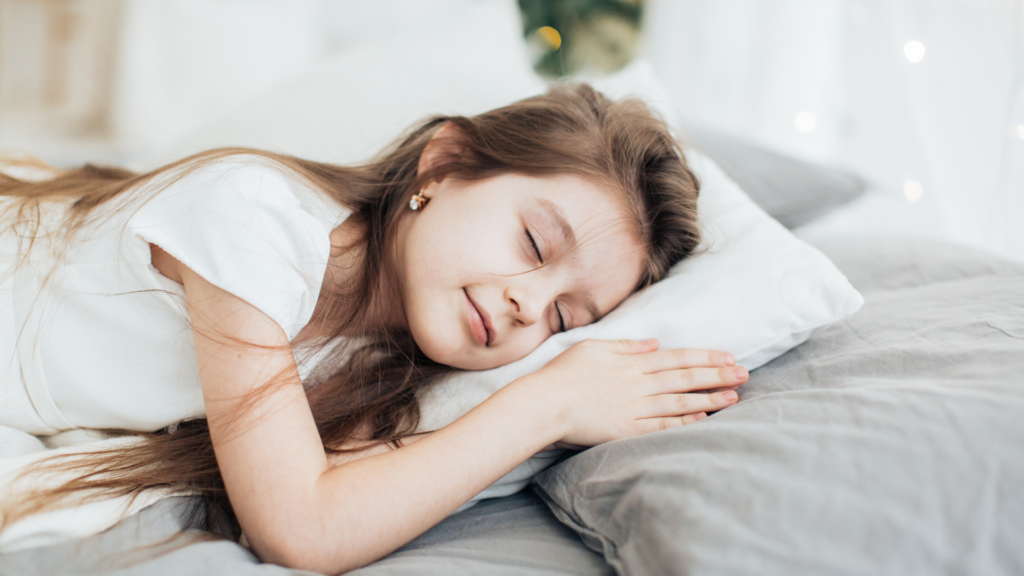 安心感のあるベッドで笑顔で眠る女の子の画像