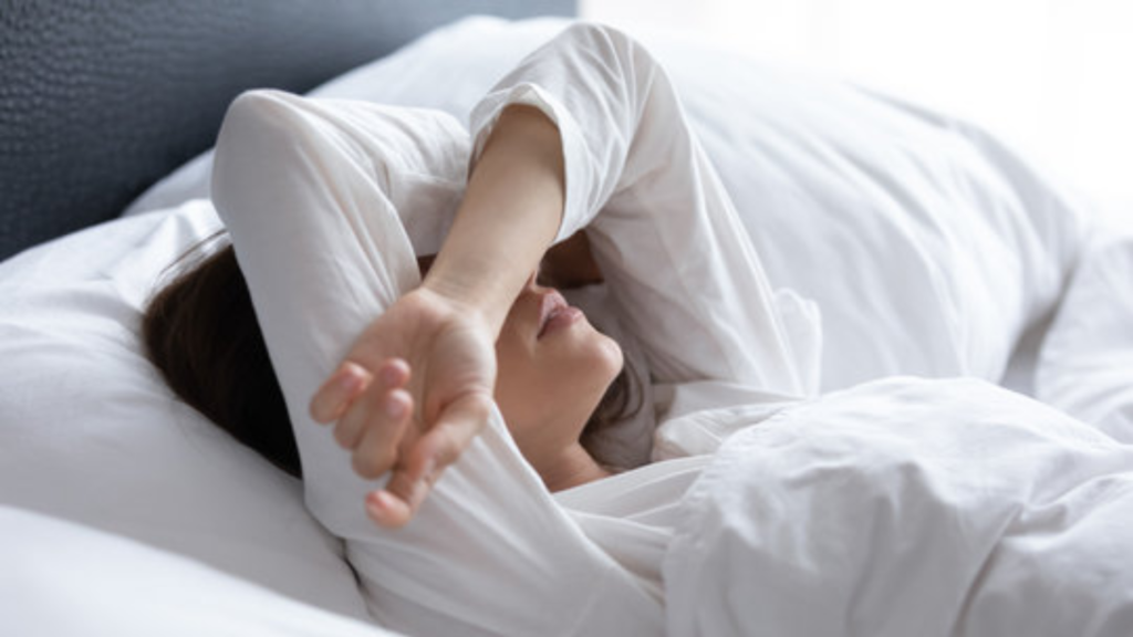 よく眠れず、ベッドの上で悩む女性の画像