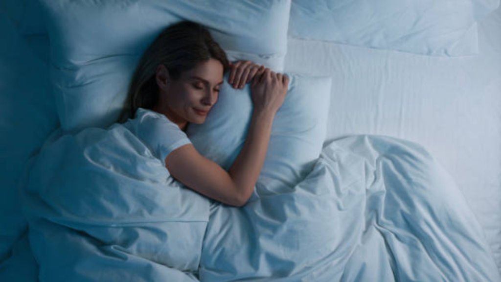 枕を抱えて横向きで眠る女性の画像